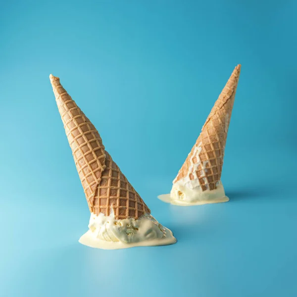Dos helados derretidos con conos de helado sobre fondo azul pastel. Concepto mínimo de comida de verano . — Foto de Stock