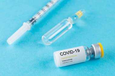 Coronavirus aşı şişesi. Mavi arka planda şırınga var. Covid-19 ilaç aşısı konsepti. Dünya salgını konsepti.