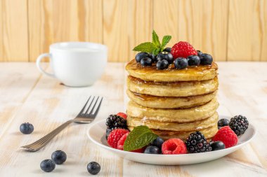 Beyaz ahşap masada taze böğürtlenli leziz krepler. Yiyecek konsepti.