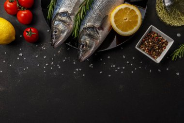 Siyah tabakta biberiye ve sebzeli iki taze deniz kabuğu balığı. Deniz ürünleri konsepti.