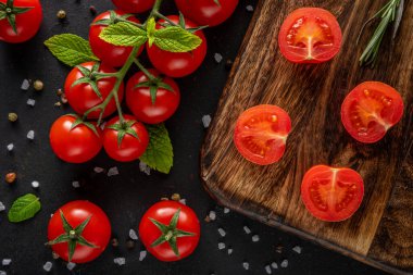 Siyah arka planda baharatlı taze kiraz domatesleri. Yemek arkaplanı. Üst görünüm.