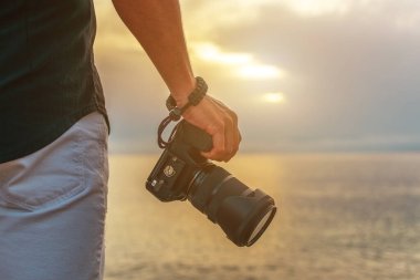 Adam gün batımında elinde bir kamera tutuyor..