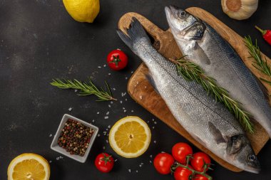 Siyah masada biberiyeli ve sebzeli iki taze deniz kabuğu balığı. Deniz ürünleri konsepti.