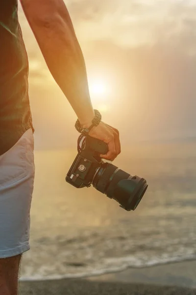 男は日没時に手にカメラを持っている — ストック写真