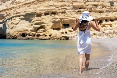 Tropik bir plajda şapkalı mutlu bir kadın. Yaz tatili kavramı.