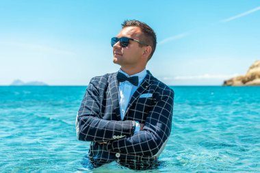 Papyonlu takım elbiseli mutlu adam denizde duruyor. Yaz tatili kavramı.