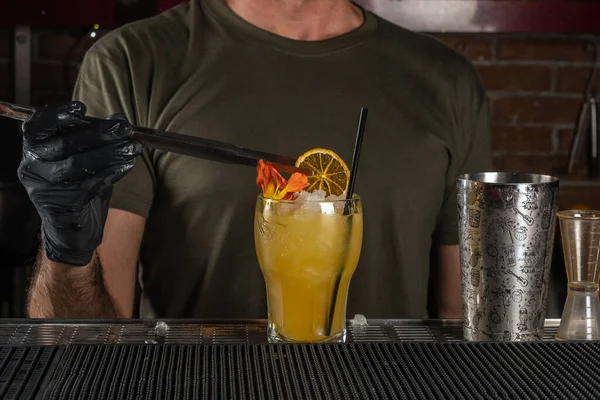 バーのバーテンダーは氷とオレンジでアルコールカクテルを作っています サマーパーティーの背景 — ストック写真