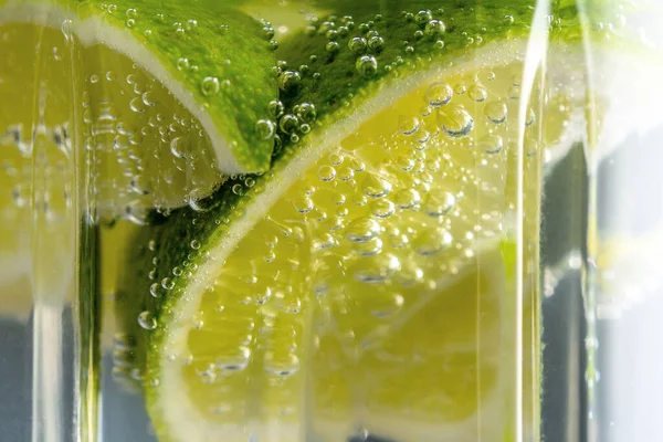 Lime slice with a drops in fizzy sparkling water. Summer drink concept.