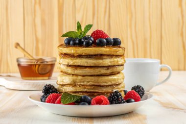 Beyaz ahşap masada taze böğürtlenli leziz krepler. Yiyecek konsepti.