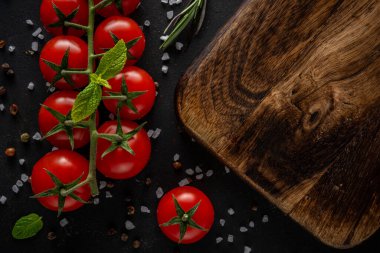 Siyah arka planda baharatlı taze kiraz domatesleri. Yemek arkaplanı. Üst görünüm.