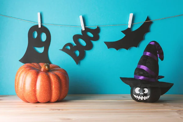 Holiday concept with funny Halloween pumpkin decor and witch hat on wooden table. Creative Halloween minimal concept.