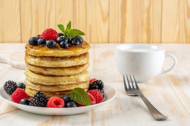 Beyaz ahşap masada taze böğürtlenli leziz krepler. Yiyecek konsepti.