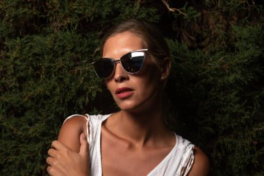 Beyaz elbiseli güzel bir kadın arka planda poz veriyor. Moda konsepti. Sert ışık.