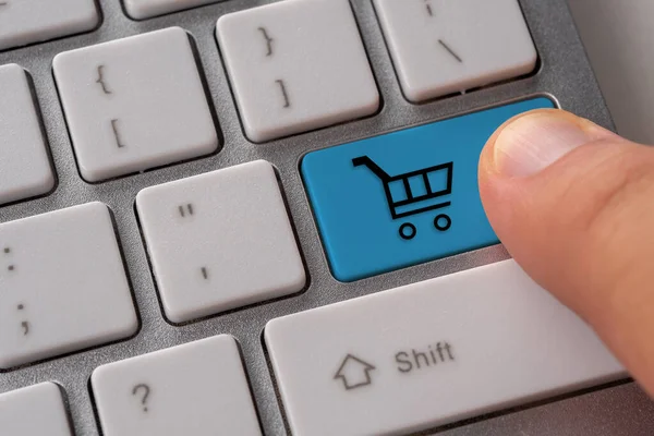 Male hand pressing keyboard button with shopping cart. Shopping online concept.