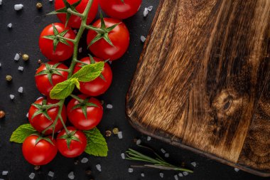 Siyah arka planda baharatlı taze kiraz domatesleri. Yemek arkaplanı. Üst görünüm.