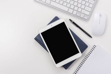 Bilgisayar klavyeli çalışma alanı, ofis malzemeleri ve beyaz arkaplanlı tablet. Kopyalama alanı olan üst görünüm.