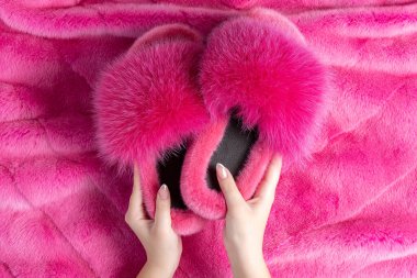 Yumuşak kürklü ekose üzerinde güzel kürk terlikleri tutan kadın elleri. Düz yatıyordu.