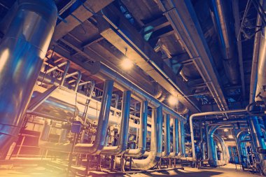 Modern bir endüstriyel santralde bulunan ekipman, kablolar ve borular. Sanayi bölgesi, çelik boru hatları, vanalar, kablolar ve yürüyüş yolu.