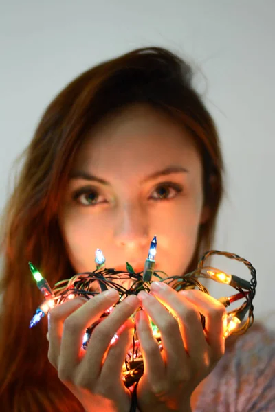 Kızın elinde Noel ışıkları var.