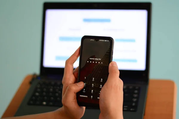 Bilgisayarın arka planında telefon tutan eller.