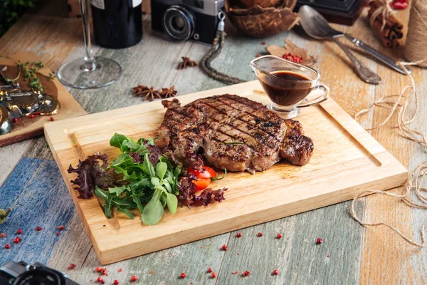 Sappige gekookte ribeye steak met saus en salade — Stockfoto