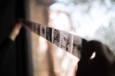 Bir adam orta formatta bir filmi bir pencereyle inceler. Eski klasiktir