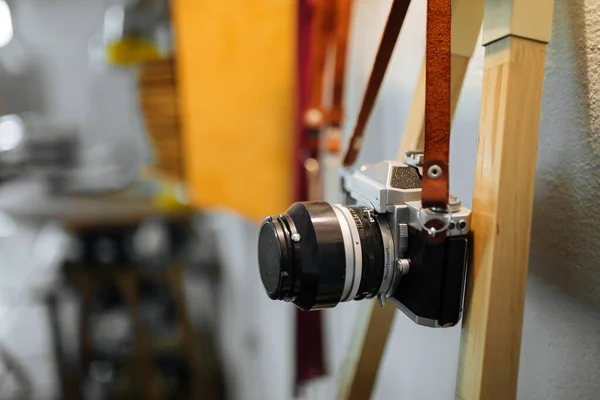 Retro film camera hangs on a strap against a white wall and a yellow warm lamp. Horizontal — Stock Photo, Image