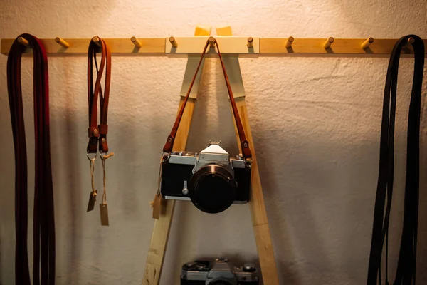 Ретро-пленочная камера висит на ремне на белой стене и желтой лампе . — стоковое фото