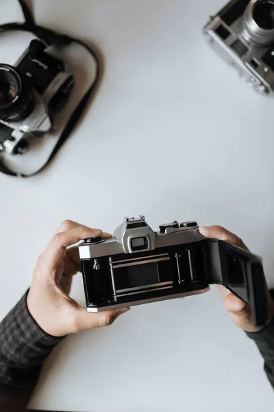 Male hands reloading film retro camera on a white table. vertical — Stock Photo, Image