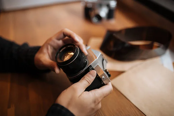 Hombre manos ajusta la cámara retro lente en una mesa de madera — Foto de Stock