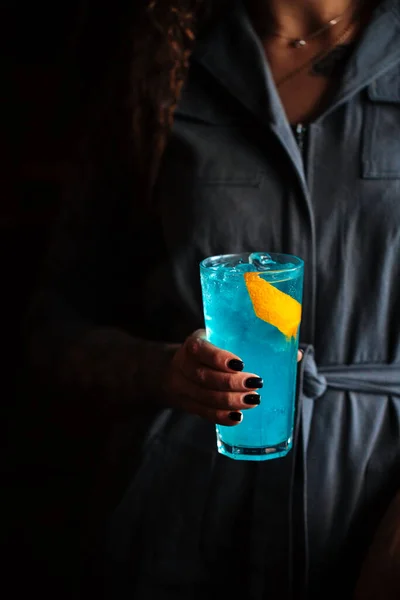 Woman holding blue cocktail in a highball with ice — Stock Photo, Image