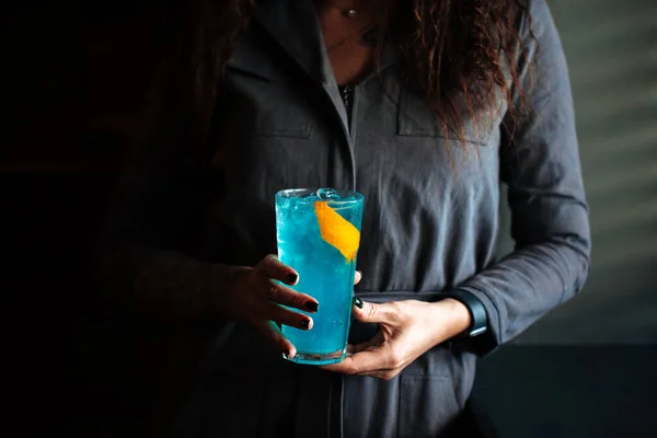 Woman holding blue cocktail in a highball with ice — Stock Photo, Image