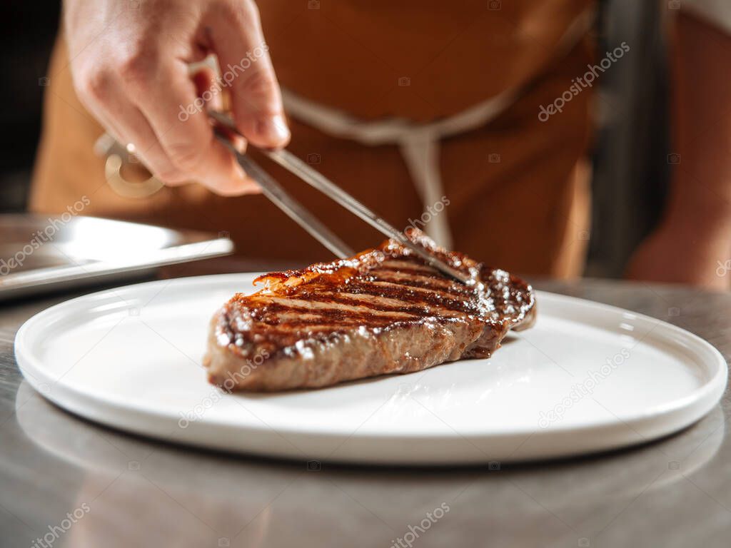 Cooked steak laid on a plate with tongs