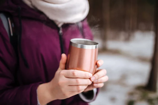 Woman holding thermo mug with hot steaming tea