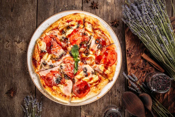 Pizza z pomidorami i oliwkami na drewnianym stole — Zdjęcie stockowe