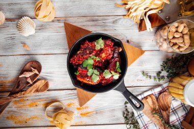 Dökme demir tavada kırmızı soslu kızarmış tavuk.