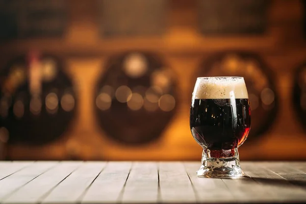 酒吧里木制桌子上杯子里的黑啤酒 — 图库照片