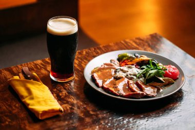 Et ve sebze tabağı ve bir bardak koyu bira.