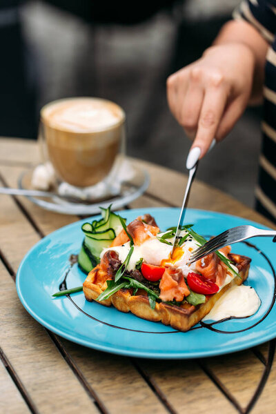 Eating waffle toast with poached egg and salmon