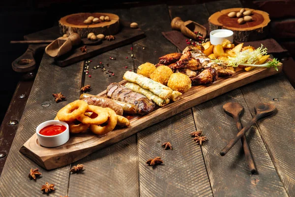 Fried beer snacks on the wooden board with sauces — Stock Photo, Image