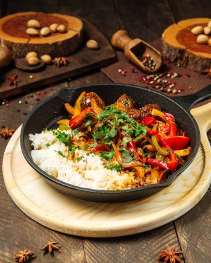 Sebzeli biftek ve dökme demir tavada pirinç.