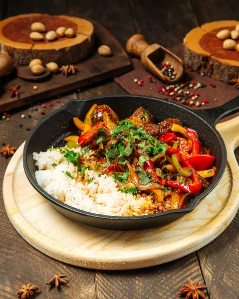 Sebzeli biftek ve dökme demir tavada pirinç.