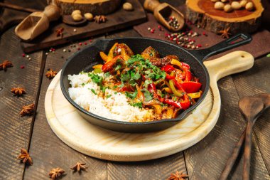 Sebzeli biftek ve dökme demir tavada pirinç.