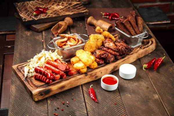 Fried beer snacks on the wooden board with sauces — Stock Photo, Image