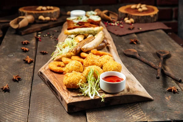 Fried beer snacks on the wooden board with sauces — Stock Photo, Image