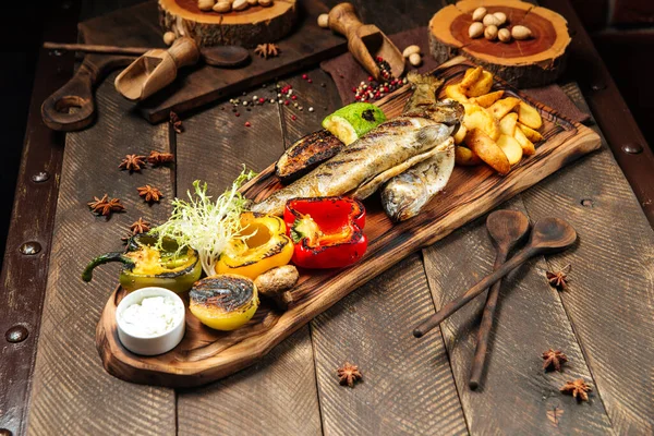 Poisson grillé aux légumes sur la planche de bois — Photo