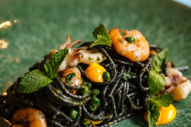 Deniz ürünleri ve safran soslu siyah spagetti.