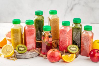 Yeşil kapaklı plastik şişelerde çeşitli taze meyve kokteylleri.