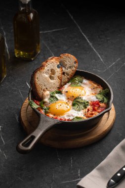 Bitkilerle taze pişmiş yumurtalar ve tost karanlık bir taş masada küçük bir tavada servis ediliyor.