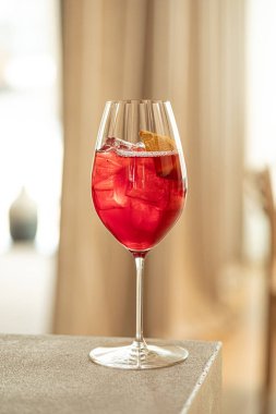 Kırmızı kokteyl, portakal dilimli ve buzlu zarif şarap kadehi.